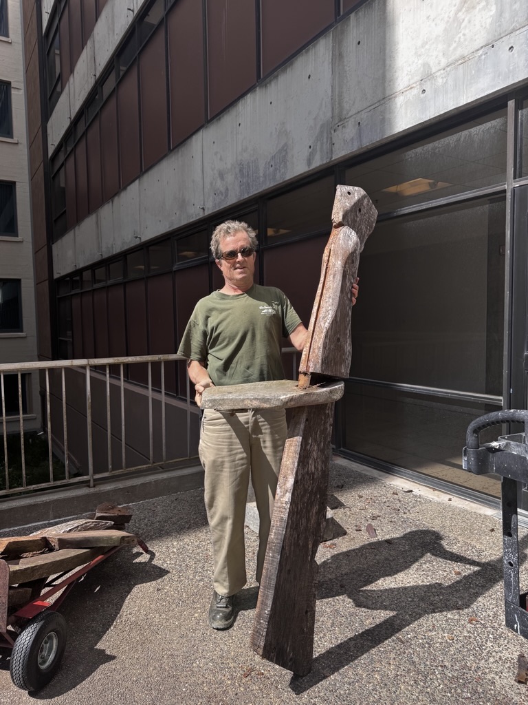 Jeremy Light with his father, Alvin Light's, wooden sculpture, which was removed from the School of Nursing Building in May 2025.